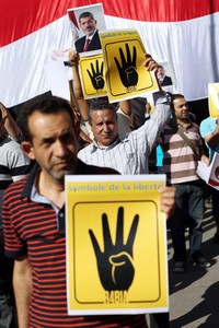 Mereka membawa poster Mursi dan simbol 4 jari R4BIA yang merupakan simbol dari pembantaian militer Mesir terhdap demonstran di Rabaa al-Adawiya. AFP/Thomas Samson.