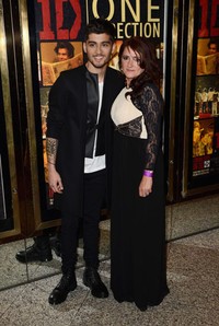 Berpose bersama sang ibu Tricia Malik, Zayn Malik terlihat necis mengenakan jaket kulit dengan luaran mantel panjang, dipadu dengan kemeja putih dan celana jeans hitam. Ian Gavan/Getty Images.