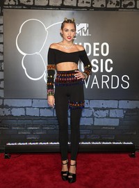 Miley Cyrus memilih setelan dari Dolce & Gabbana dengan crop top lengan panjang dan legging hitam dihiasi dengan ornamen berwarna-warni dipadu dengan sepatu dari Giuseppe Zanotti dan perhiasan Lorraine Schwarz. REUTERS/Andrew Kelly.
