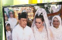 Prosesi akad nikah ditayangkan di televisi yang diletakkan di luar rumah.