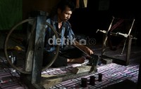 Seorang bapak memintal  benang untuk digunakan membuat ulos, tradisi ini telah mereka lakukan turun menurun.     