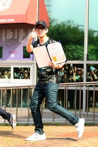 Ia yang bergaya dengan kacamata dan topi itu berjalan keluar dari kantor Distrik Seongdong, Seoul, Korsel, mengenakan kaus hitam bercorak, celana denim, dan sepatu putih. TenAsia/Paeng Hyun Jun.