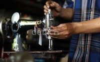 Pekerja melakukan servis mesin jahit di daerah H. Ung, Kemayoran.