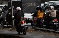 Pengendara sepeda motor melintas di atas trotoar.