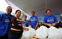 Seorang warga mengambil paket sembako yang dibagikan.