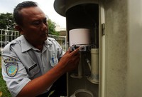     Petugas mengecek curah hujan menggunakan alat bernama penakar hujan.