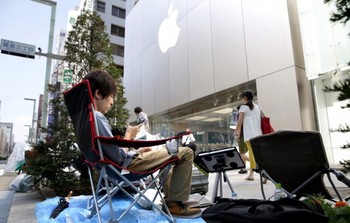     Seorang fans Apple sudah mengantre di depan Apple Store Ginza di Jepang. Untuk menghabiskan waktu, ia asyik bermain ponsel. (kredit foto: Getty Images)