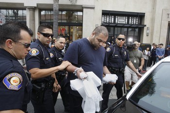 Pria yang dituduh tidak membayar sesuai perjanjian dibawa polisi untuk diperiksa lebih lanjut. (kredit foto: Gary Friedman / Los Angeles Times)