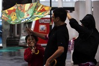 Tiga orang warga berjuang menghadapi Topan Usagi. Payung yang digunakan untuk berlindung dari air hujan pun tak kuat menahan terpaan angin. ReutersTyrone Siu.