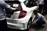Petugas Dishub DKI Jakarta mencabut pentil salah satu mobil yang parkir sembarangan.