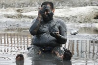 Seorang pria menutupi tubuhnya dengan lumpur sambil duduk di kolam lumpur obat di Lagoon of Miracles di Chilca. (Foto: Reuters)