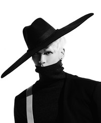 Jonghyun mengenakan blus hitam dengan aksen turtle neck dan topi yang besar. (SME)
