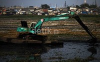 Pekerja dengan menggunakan eskafator mengeruk lumpur di Waduk Pluit, Jakarta Utara, Selasa (08/10/2013).