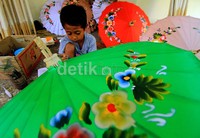 Seorang anak ikut menyapukan kuas sepulang sekolah. Kesinambungan regenerasi inilah yang selalu dijaga agar kerajinan payung Juwiring tidak punah dimakan jaman.