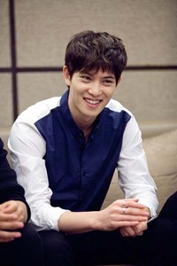 Meski tak banyak bicara, Jonghyun selalu menebar senyuman selama jumpa pers berlangsung. (FNC Entertainment/W Productions)