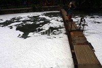 Warga melintasi kali sunter yang dipenuhi busa, Rabu (23/10/2013).