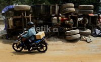Pemotor melintas di depan truk yang terguling.