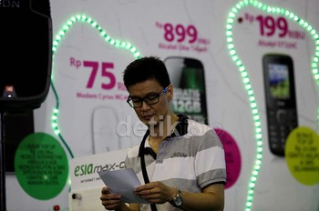 Seorang calon pembeli membaca brosur esia murahnya juara di depan banner yang terpasang di booth.