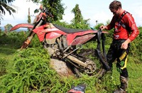 Riders asal Australia menambal ban motornya sendiri di tengah hutan.