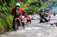 Dua orang peserta berusaha menyeberangi sungai sedalam lutut orang dewasa.