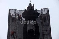 Petugas membersihkan patung Monumen Pemuda Membangun di bundaran air mancur Senayan.