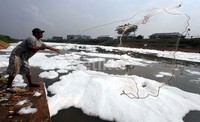 Sejumlah warga menjaring ikan di antara busa-busa di Banjir Kanal Timur.