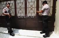 Polisi berjaga dengan menenteng senjata laras panjang.