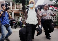 Petugas KPK membawa sebuah tas besar saat keluar dari rumah Anas.