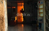 Seorang warga memadamkan api dengan peralatan seadanya.