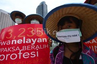 Para nelayan memakai caping dan menutup mulut mereka dengan masker bertuliskan Sejahtera Itu Hak.
