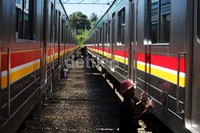 Pekerja membersihkan gerbong KRL.