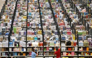 Tampak dua orang karyawan Amazon melakukan scan pada barang agar mudah dimonitor. (kredit foto: Geoff Robinson)