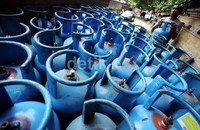 Seorang pekerja menurunkan tabung elpiji 12 kg dari atas truk.