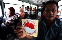 Seorang penumpang bus menunjukan stiker anti korupsi.