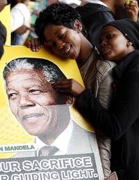 Seorang warga memeluk foto Mandela. REUTERS/Ihsaan Haffejee.