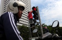 Seorang pemotor berhenti di depan lampu merah yang tengah dibersihkan.