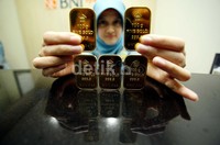 Seorang petugas menunjukkan emas batangan 100 gram di kantor pusat BNI Syariah, Jakarta, Senin (16/12/2013).