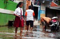 Seorang siswa tetap ke sekolah meski rumahnya terendam banjir.