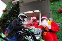 Sinterklas membagikan permen kepada pengendara sepeda motor yang mengisi BBM.
