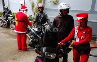 Sinterklas menyapa pengendara sepeda motor yang tengah mengantre BBM.