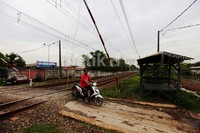 Pengendara sepeda motor melintas di pintu perlintasan KA. Saat ini, sejumlah titik perlintasan kereta telah dijaga Satpol PP, di antaranya Bintaro, Roxy, dan Jalan Angkasa.