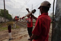 Dua orang warga menutup pintu perlintasan KA.