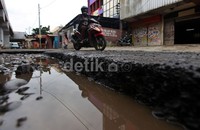 Kendaraan melintas di jalan rusak di Kalibata, Jakarta, Kamis (19/12/2013).