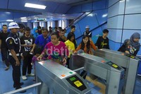 Penumpang antri dalam menggunakan gate elektronik untuk keluar stasiun.