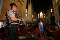 Polisi bersenjata lengkap berjaga di dalam gereja.