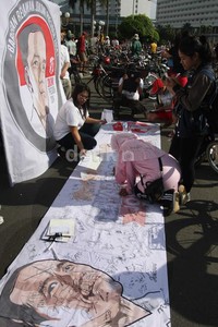 Warga memberikan tanda tangan di spanduk untuk pengumpulan tandatangan dukungan Jokowi Presiden 2014, di kawasan Bundaran HI, Jakarta Pusat, Minggu (29/12). Lamhot Aritonang/detikFoto