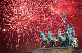     Kembang api meledak di belakang patung Quadriga di atas Gerbang Brandenburg, puluhan ribu orang bersuka ria berkumpul di pusat kota untuk merayakan malam tahun baru di Berlin, Jerman. (kredit foto: Adam Berry/Getty Images)