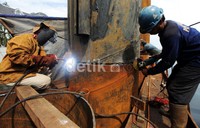 Seorang pekerja melakukan pengelasan tiang rumah pompa.