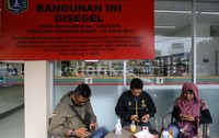 Pengunjung bersantai di depan gerai seven eleven yang ditelah disegel oleh Pemprov DKI Jakarta di Jalan Budi Kemulyaan, Gambir, Jakarta Pusat.