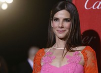 Sandra Bullock menebar senyuman manisnya di depan kamera. REUTERS/Fred Prouser.